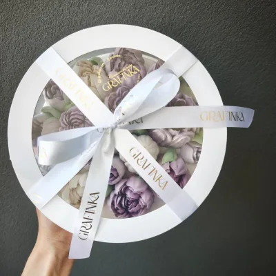 Płaskie okrągłe pudełko z segmentowym okienkiem, trzymane w dłoni